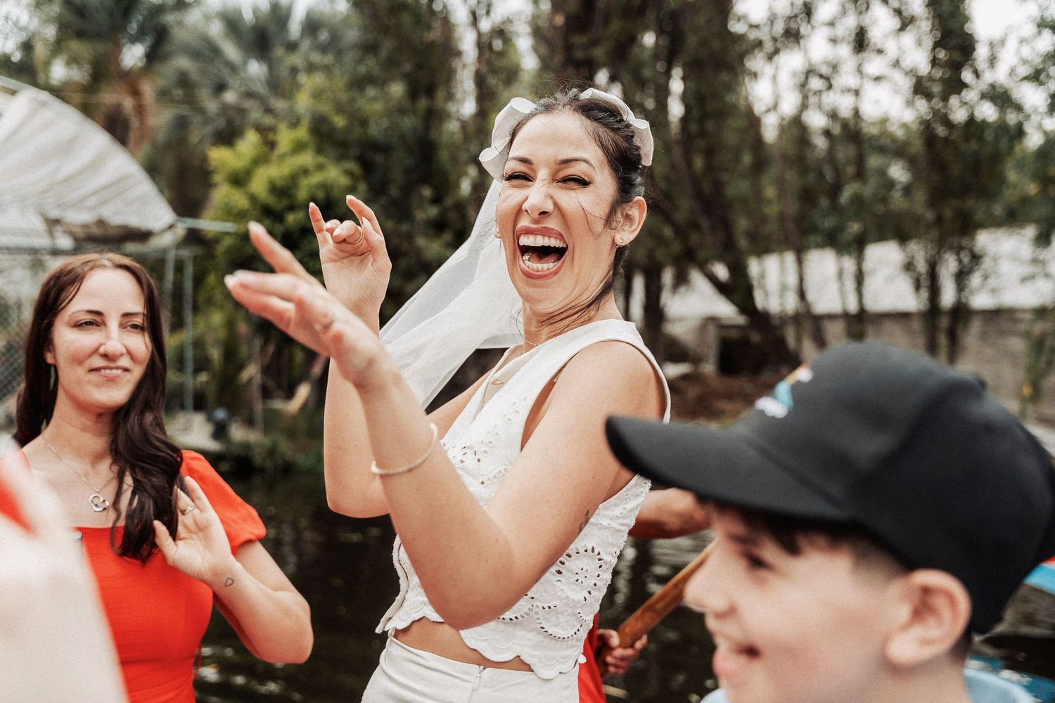 A group of people dancing and celebrating outdoors at a casual daytime event with palm trees in the background.