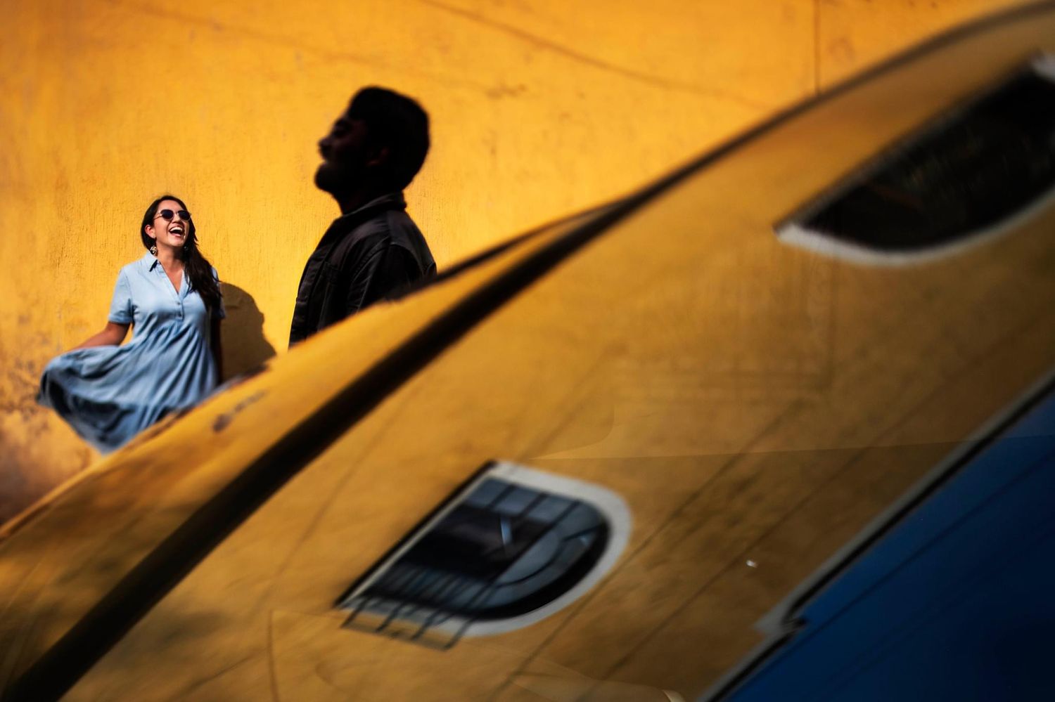 An artistic wedding photo with dramatic shadows against a yellow wall.