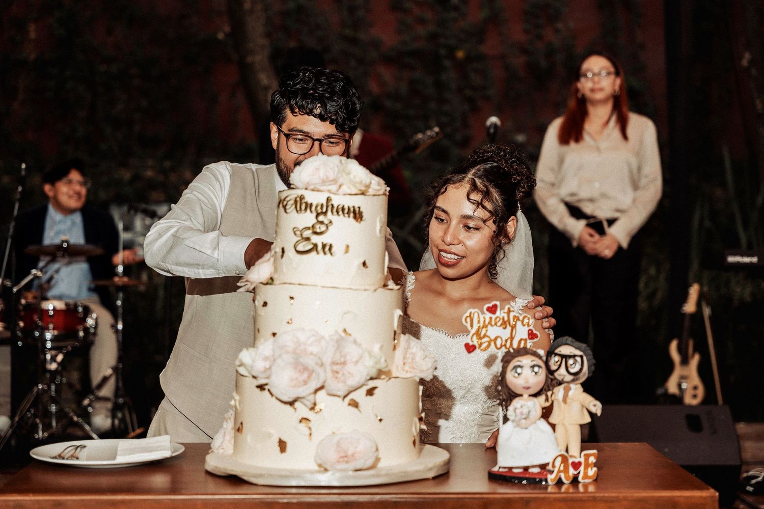 Wedding celebration showing the festive cake cutting moment with guests watching in a dimly lit reception venue.