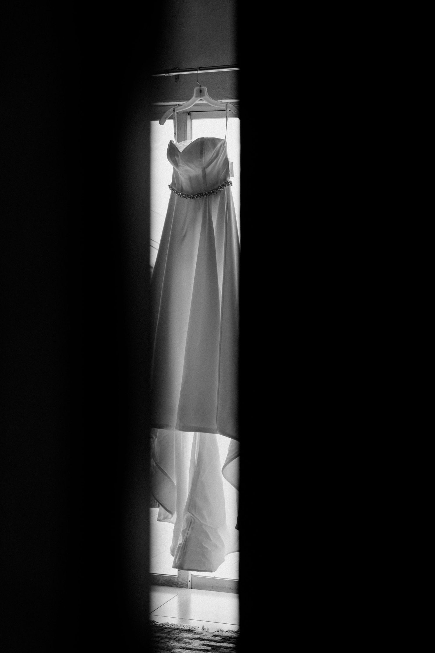 A series of black and white photographs showing a white dress hanging in a closet from different angles.