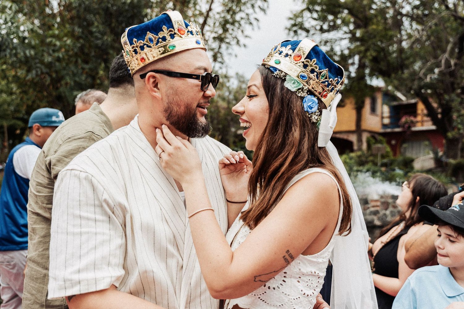 Two people wear matching paper crowns and celebrate a special moment together in an outdoor setting.