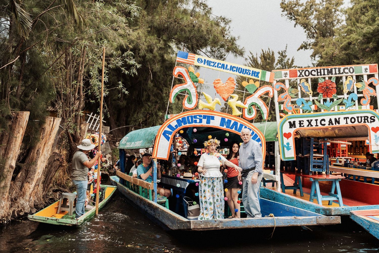 Colorful tourist boats and vendors lined up at the famous Xochimilco canals in Mexico City on a sunny day.