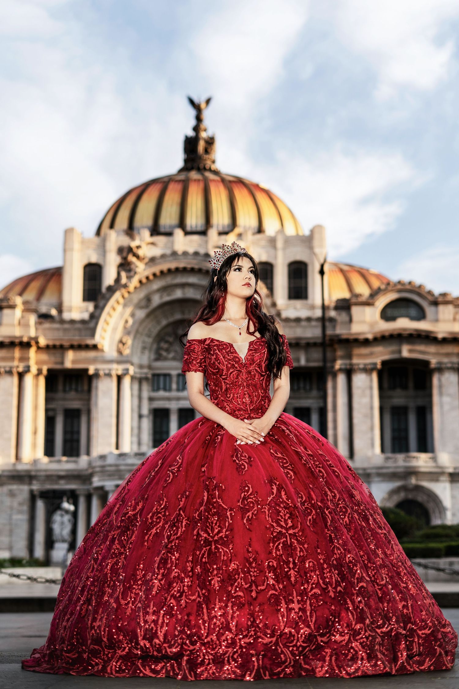 A stunning red ballgown with intricate embroidery photographed in front of the Palacio de Bellas Artes in Mexico City.