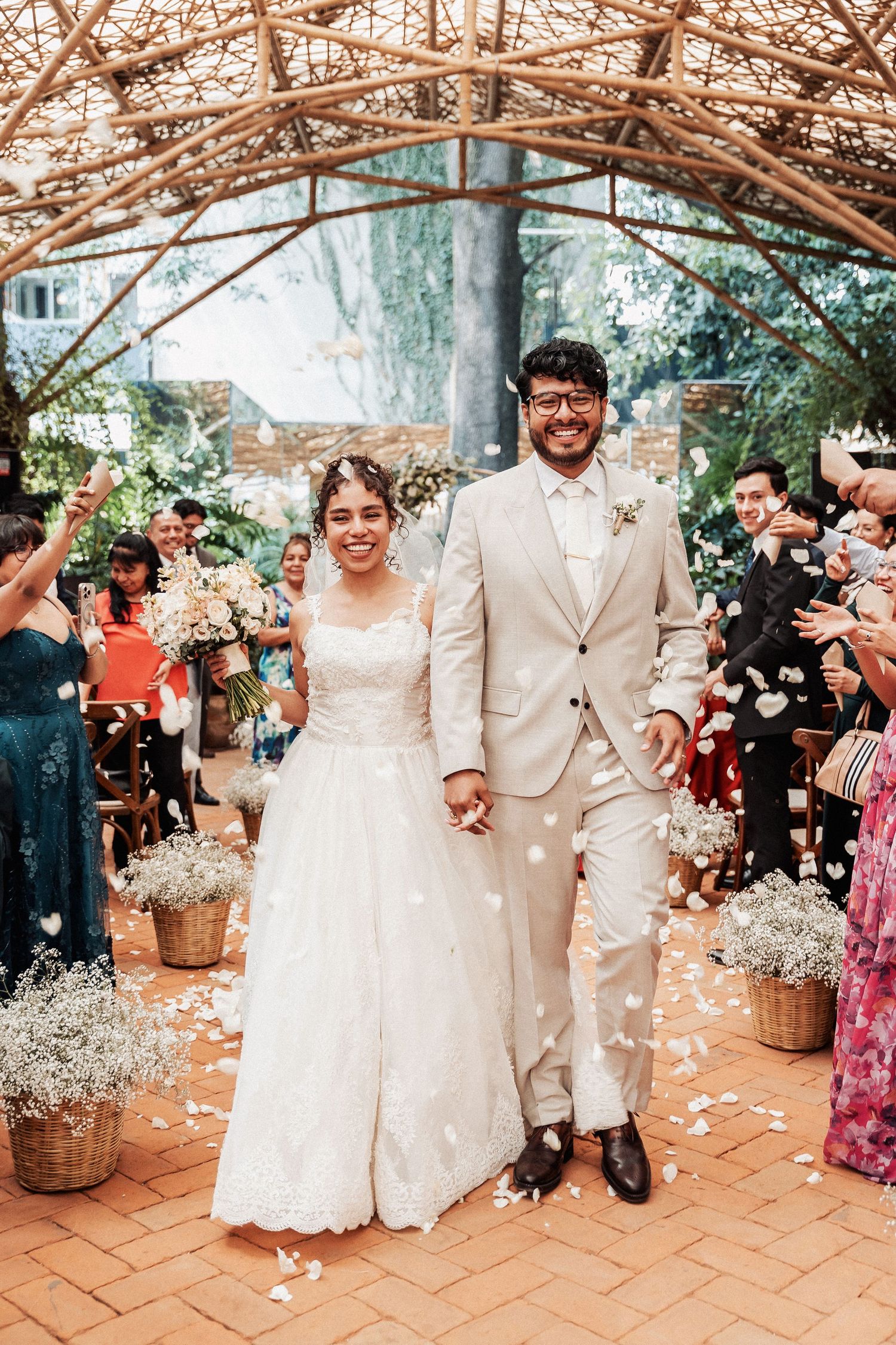 Wedding ceremony under a rustic pergola decorated with floral arrangements and confetti celebrations.