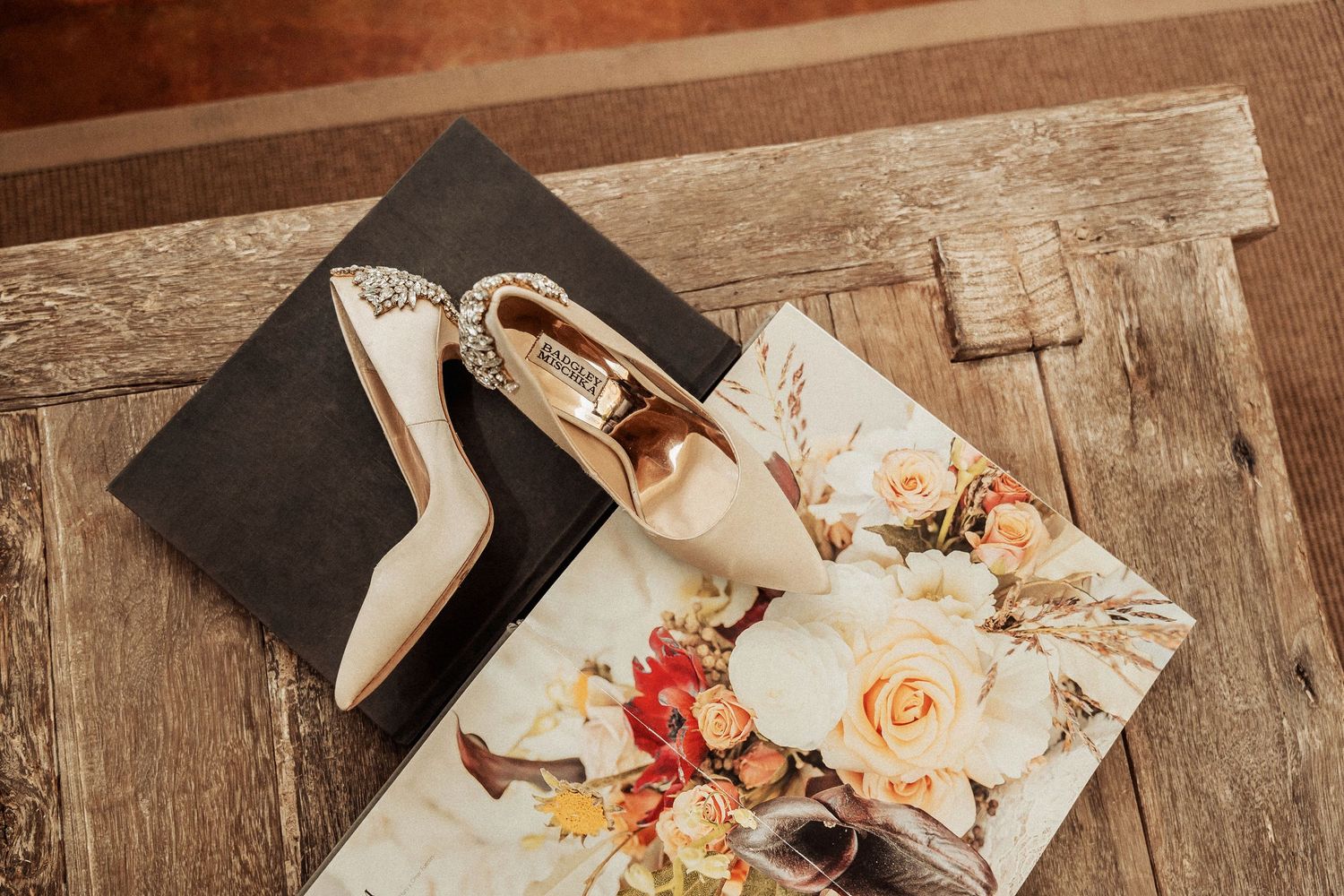 Elegant white bridal heels and wedding album displayed on a vintage wooden surface.