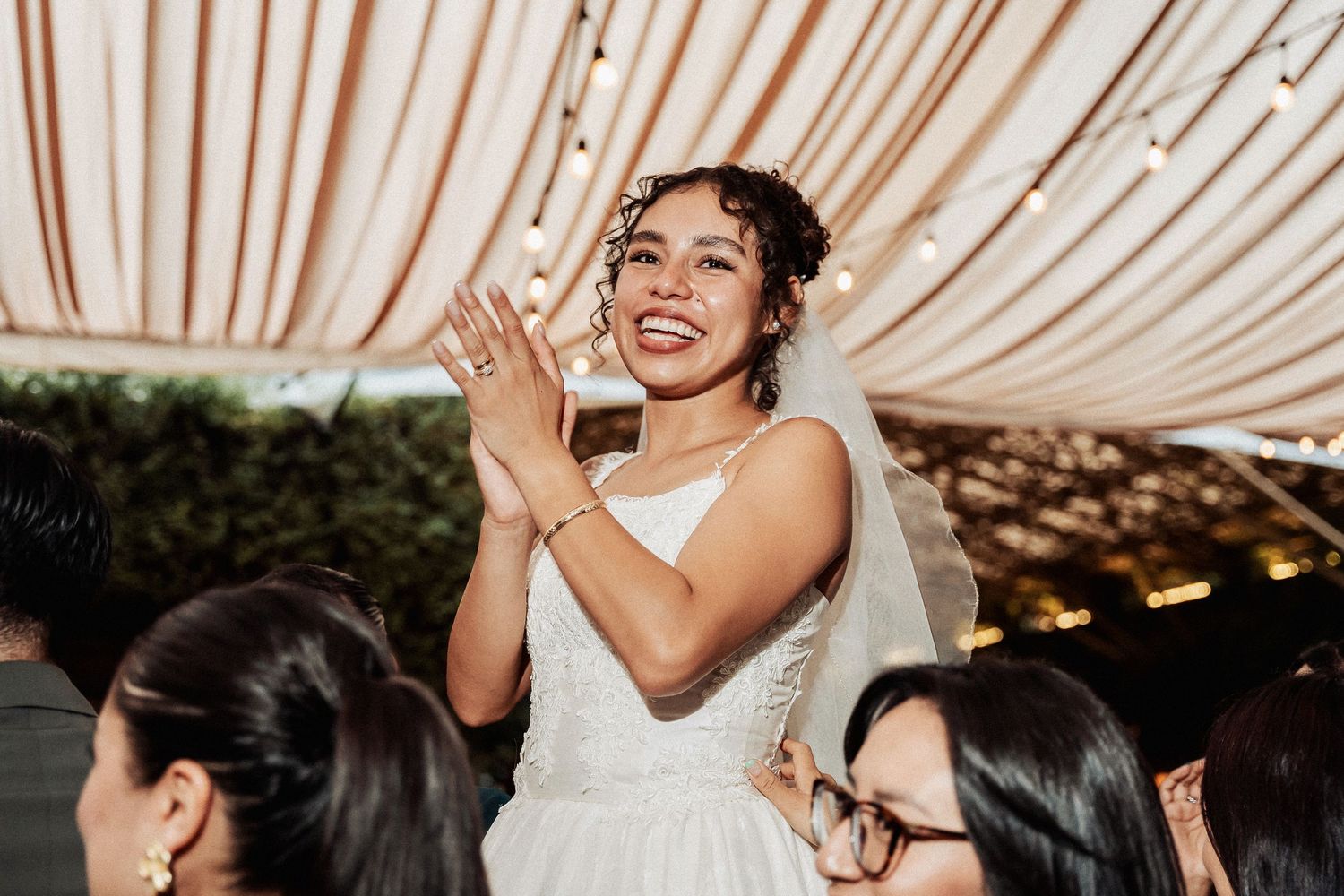 Wedding celebration under draped fabric ceiling with string lights creating an elegant atmosphere.