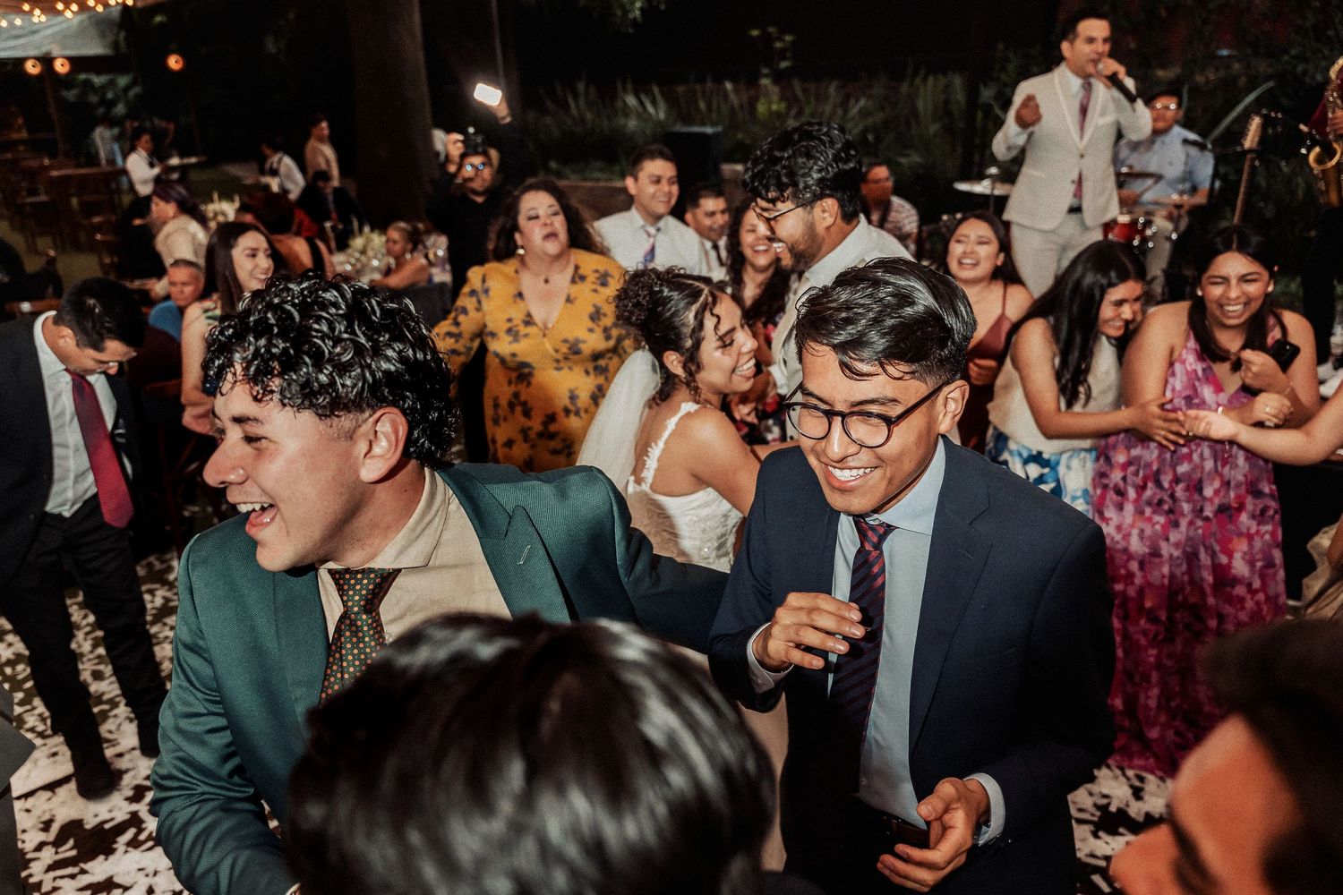 Energetic wedding reception scene with guests dancing and socializing at an indoor celebration.