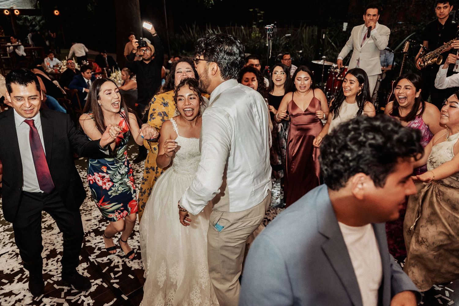 Guests celebrating on a lively dance floor with confetti flying through the air at a wedding reception.