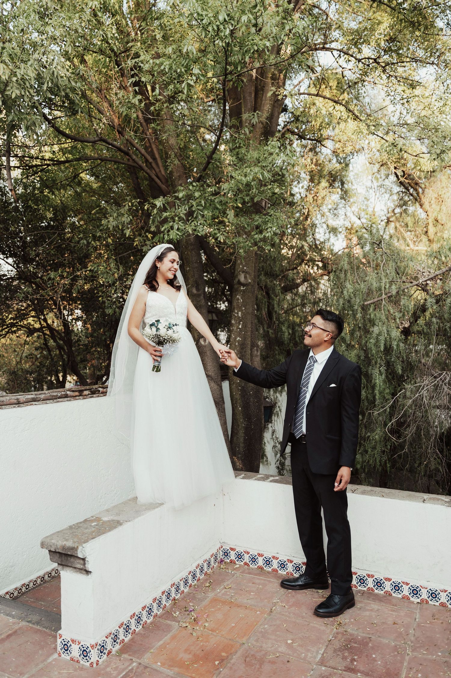 A couple shares a moment on tiled steps surrounded by lush greenery.