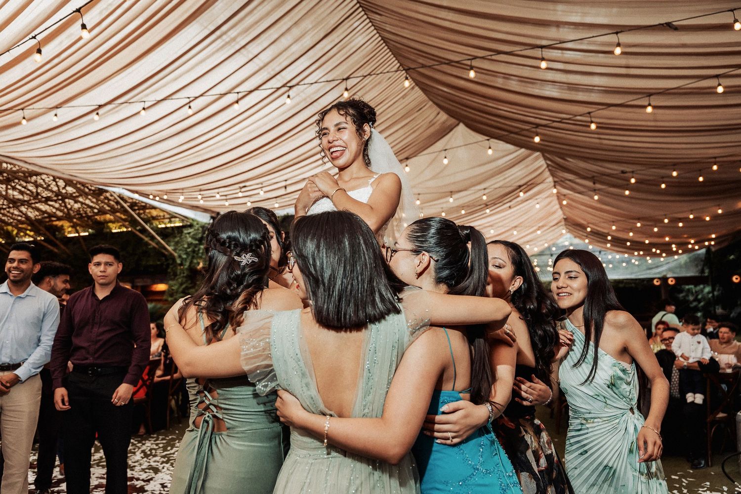 Group of people in formal attire dancing and celebrating at wedding reception.