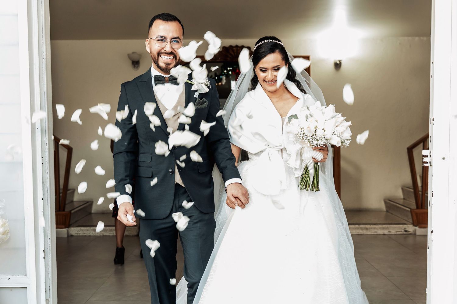 A joyful wedding exit with white flower petals raining down on the newlyweds.