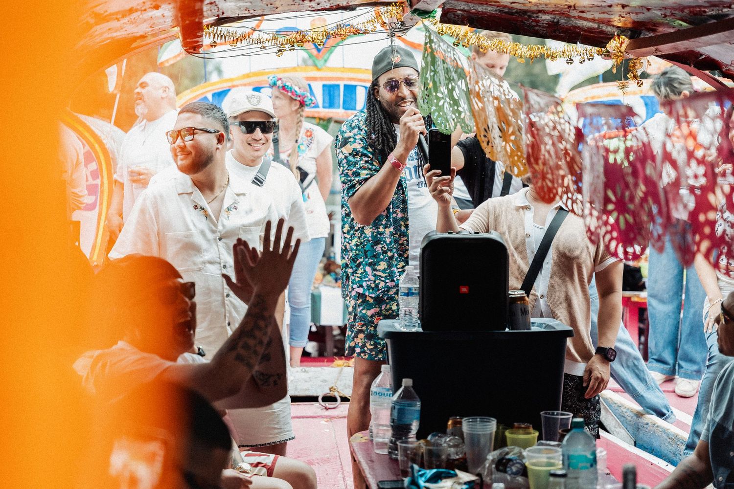 Musicians perform during an outdoor party with vibrant colorful graffiti backdrop and enthusiastic crowd.