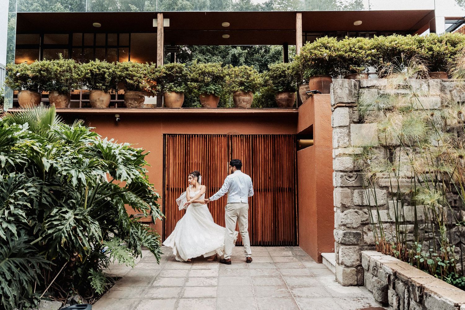 An outdoor wedding venue with stone walls and lush greenery along a walkway.