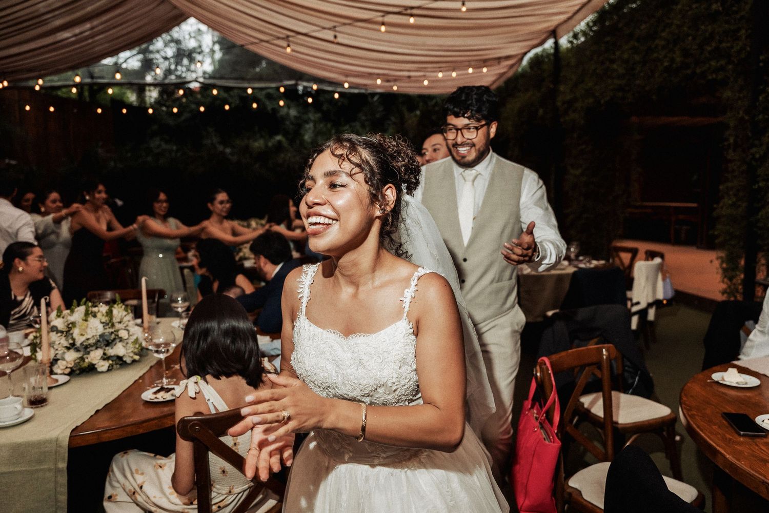 Candid reception moment showing celebration under draped fabric and string lights.
