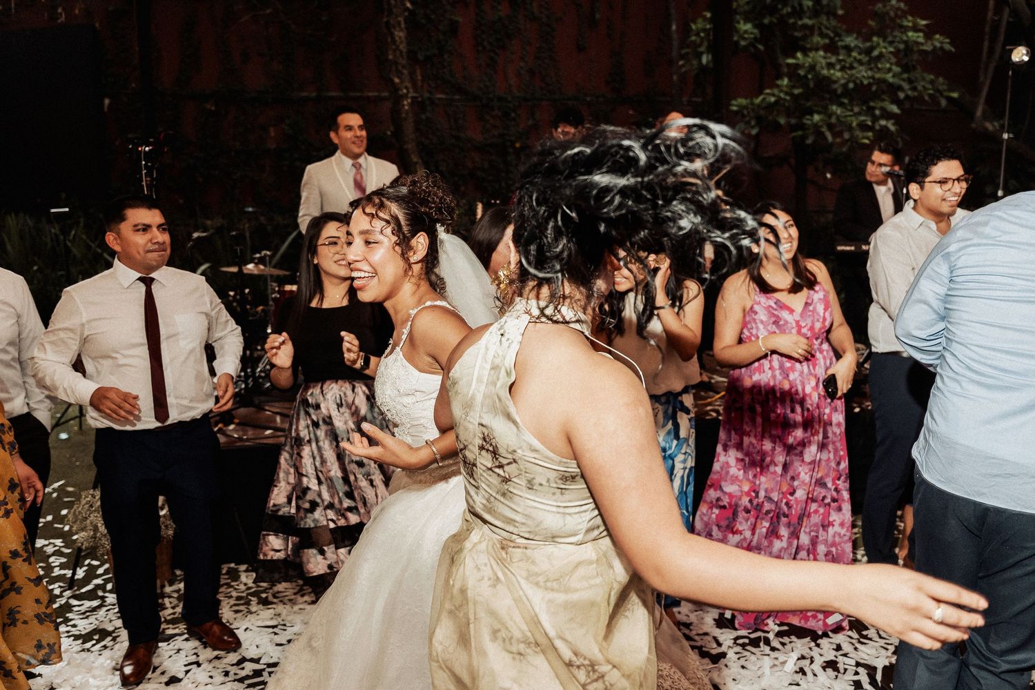 Joyful reception celebration with guests dancing and spreading confetti on the dance floor.