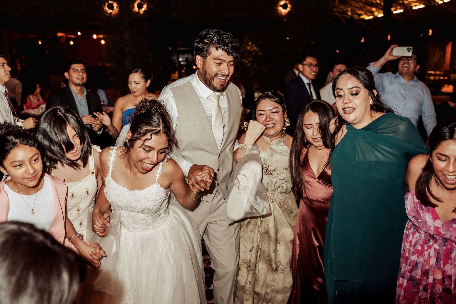 Lively dance floor scene with wedding guests celebrating at an evening reception.