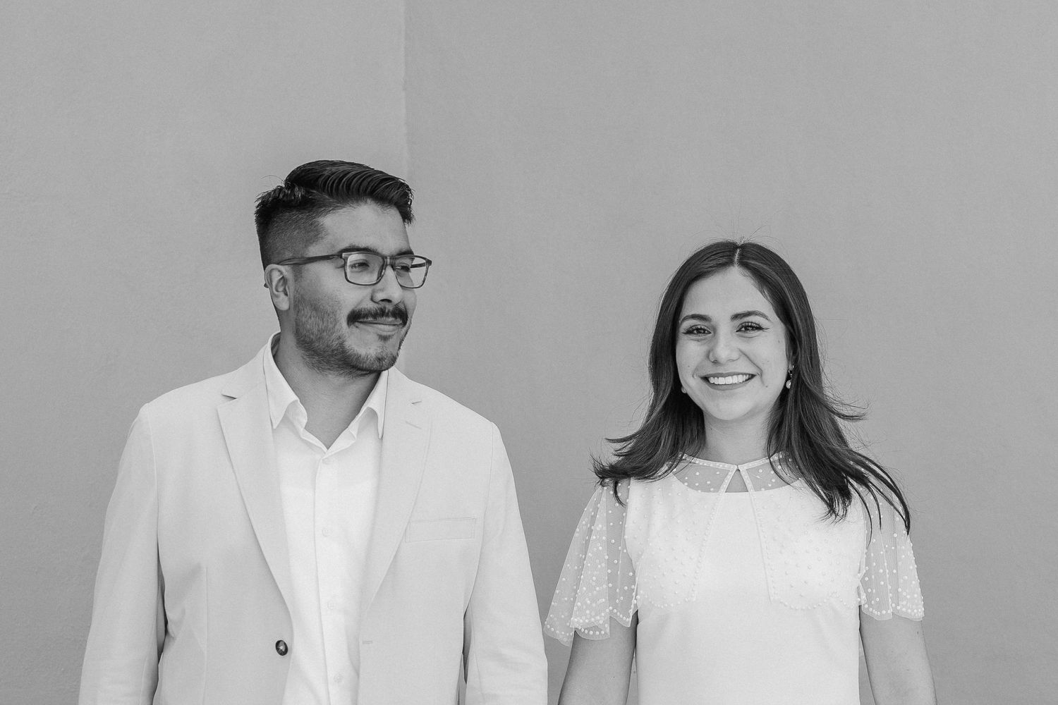 A minimalist portrait of a couple against a grey background.