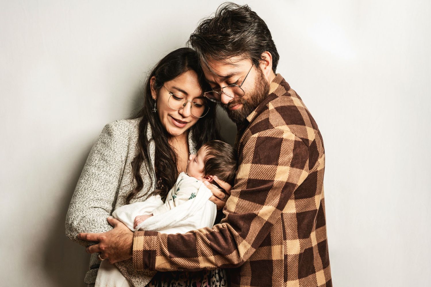 A cozy indoor family portrait showing tender moments with a newborn baby.
