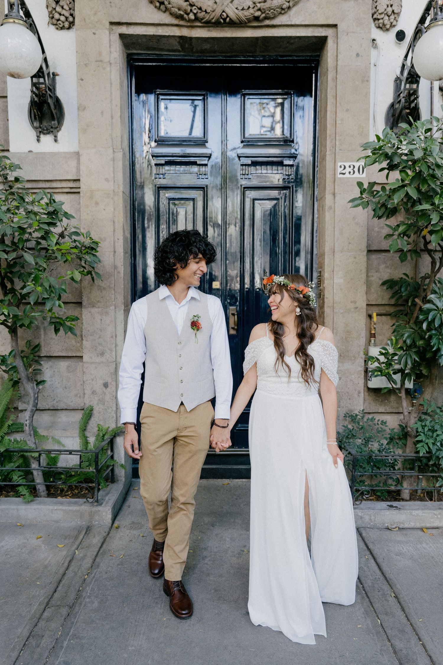A couple in wedding attire shares romantic moments outside a vintage blue door in an urban setting.