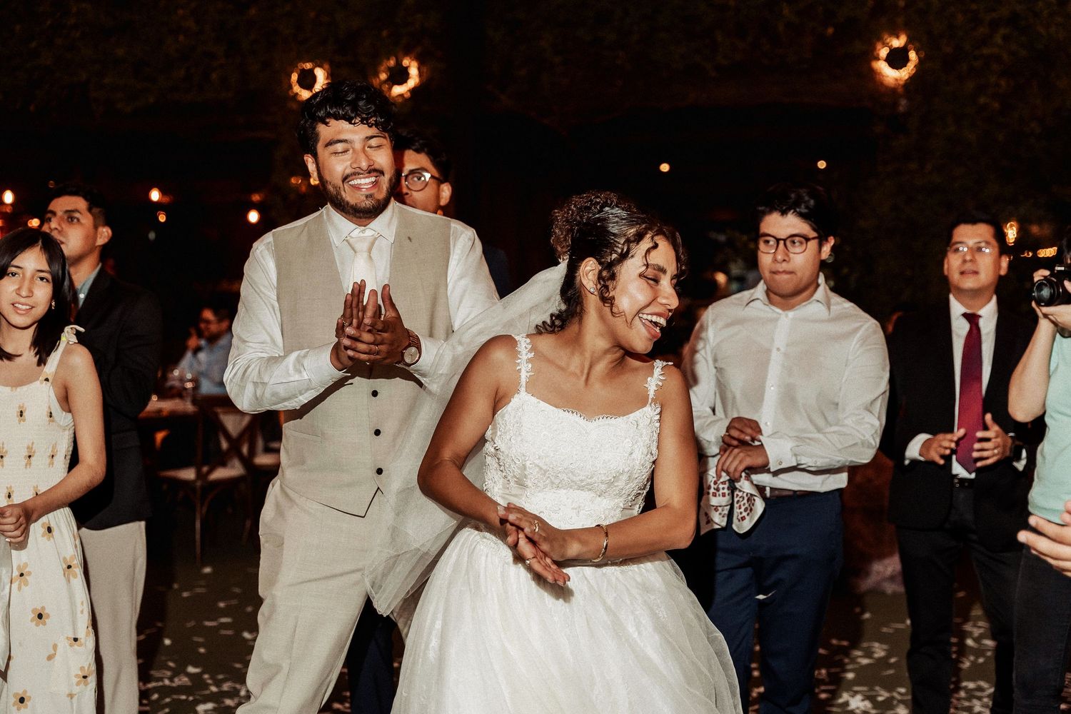 Wedding reception dance floor filled with joyful guests celebrating under evening lighting.