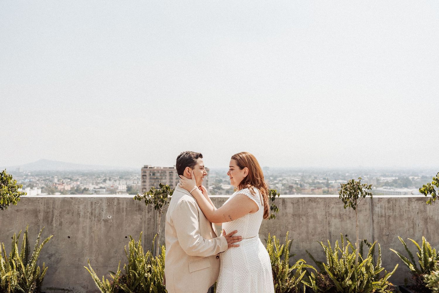 Two brides share an intimate rooftop moment with cityscape views.