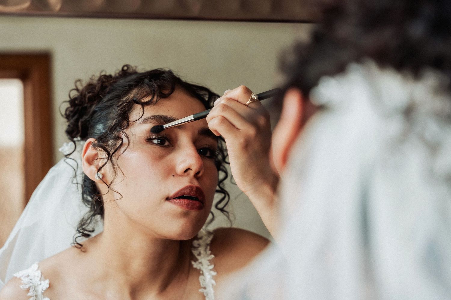 Close-up side view of bride having her makeup professionally applied during wedding preparations.