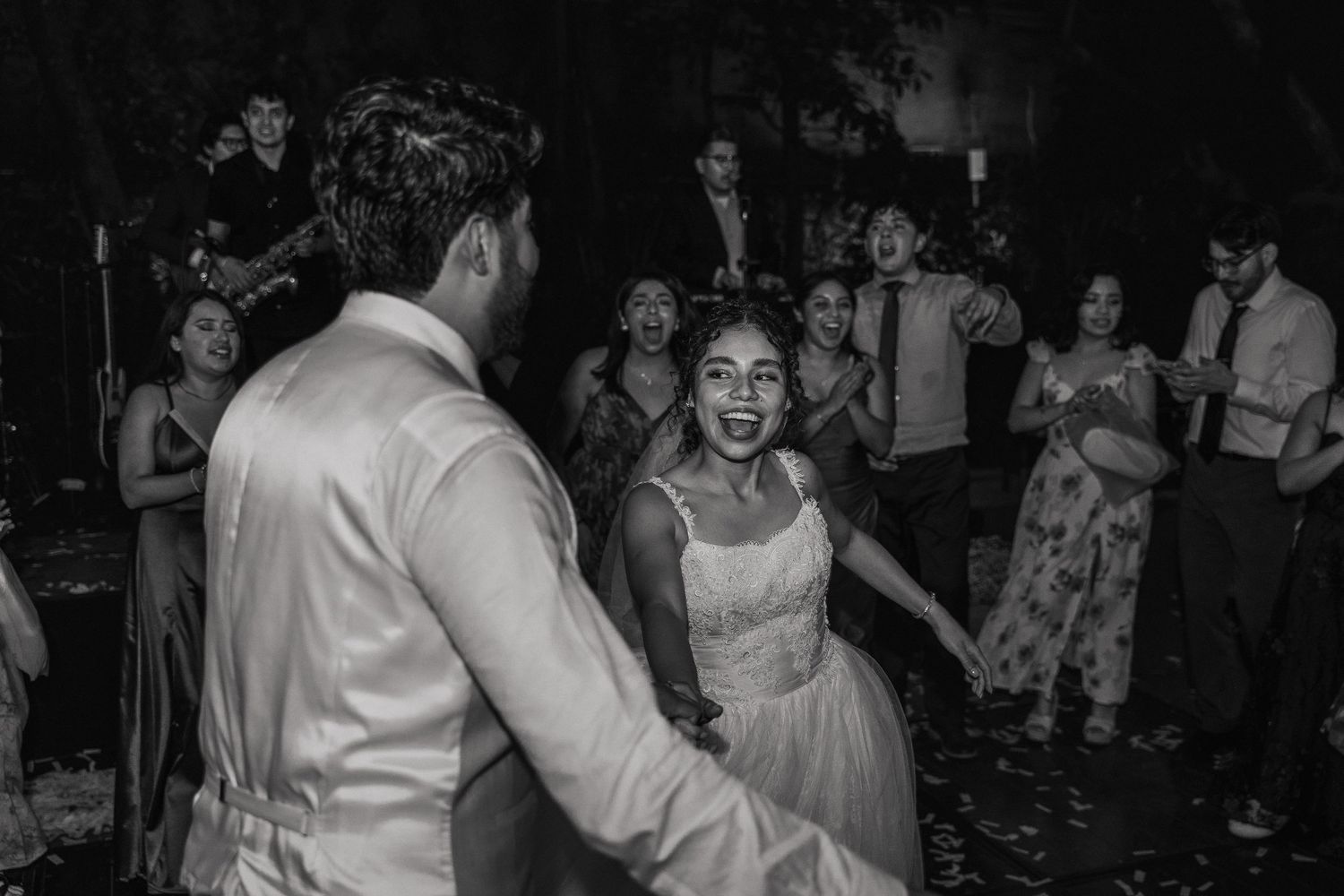 Black and white photo of guests dancing and celebrating at a wedding reception.