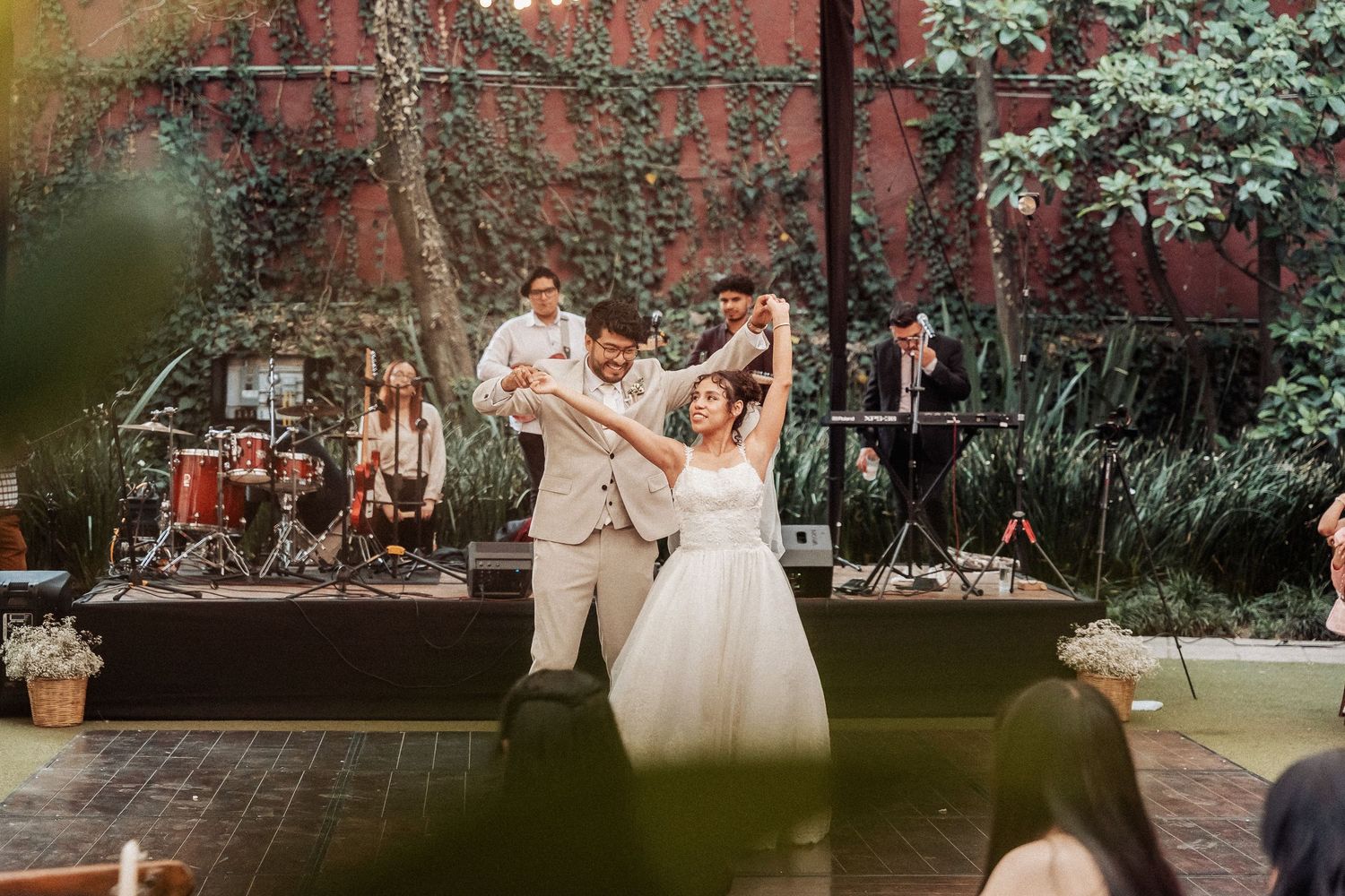 Wedding celebration outdoors with guests dancing and enjoying festivities in a garden setting.