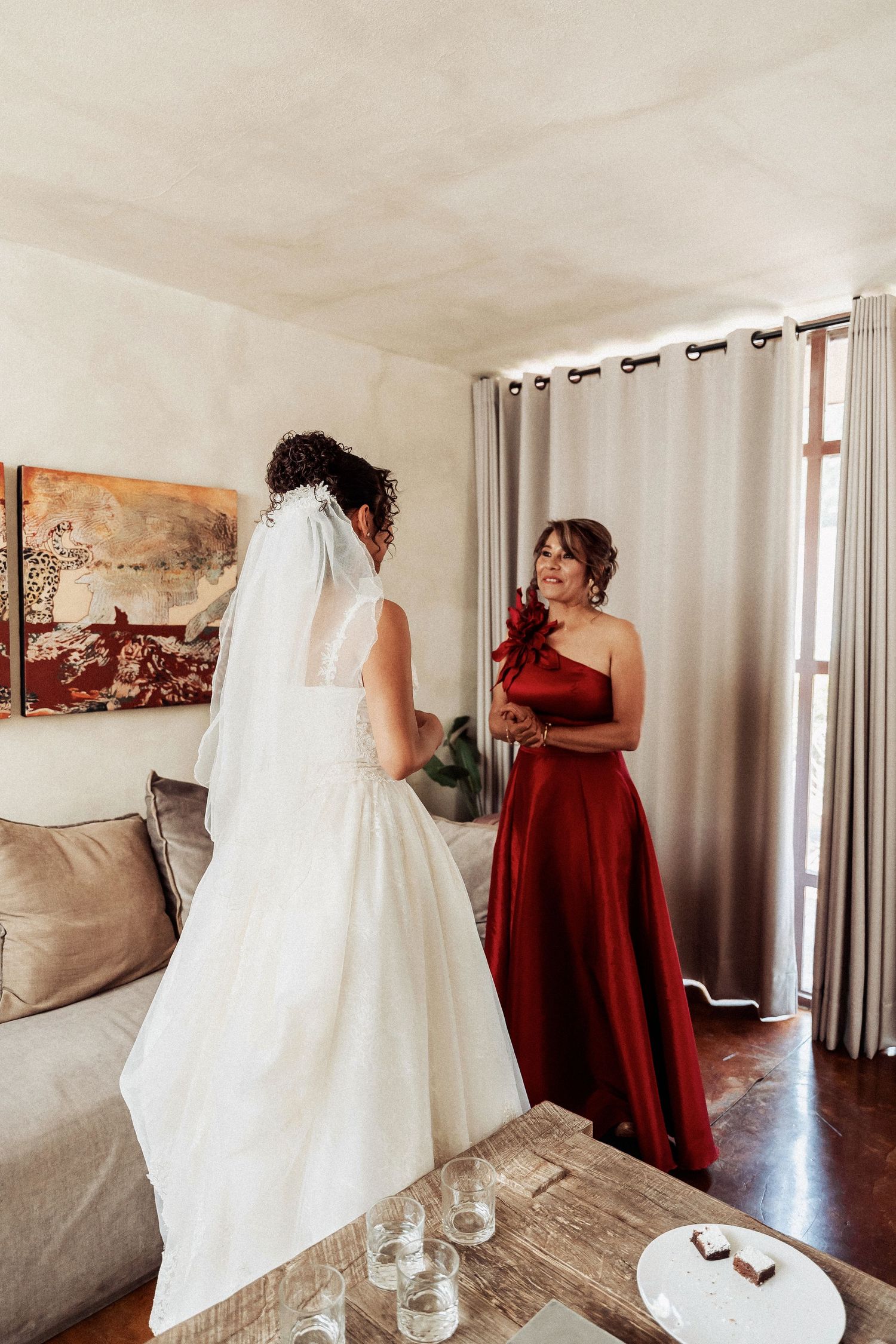 Wedding party getting ready with white bridal gown and burgundy bridesmaid dresses in a bright modern room.