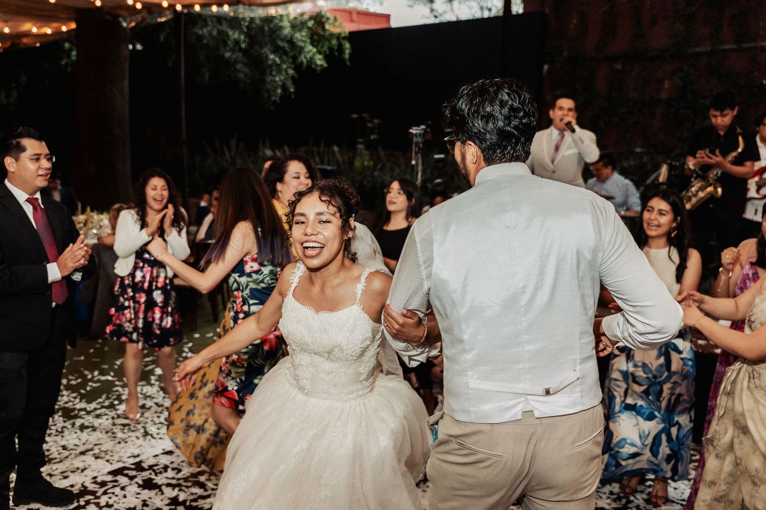 Wedding reception dance floor filled with celebrating guests under string lights.
