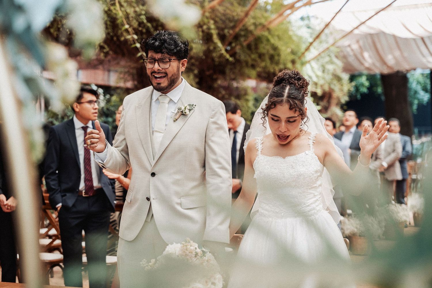 Joyful newlyweds celebrate while walking together at their outdoor garden reception venue.