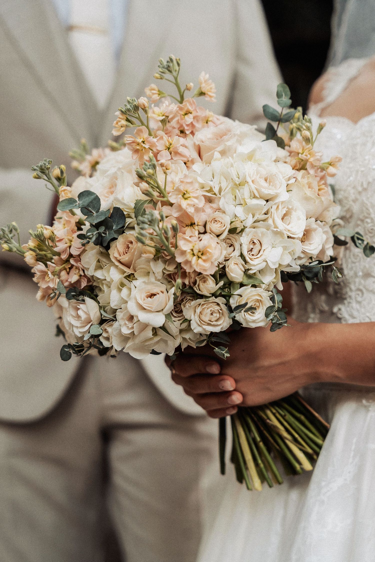 A romantic wedding bouquet with soft peach and cream roses mixed with delicate greenery eucalyptus.