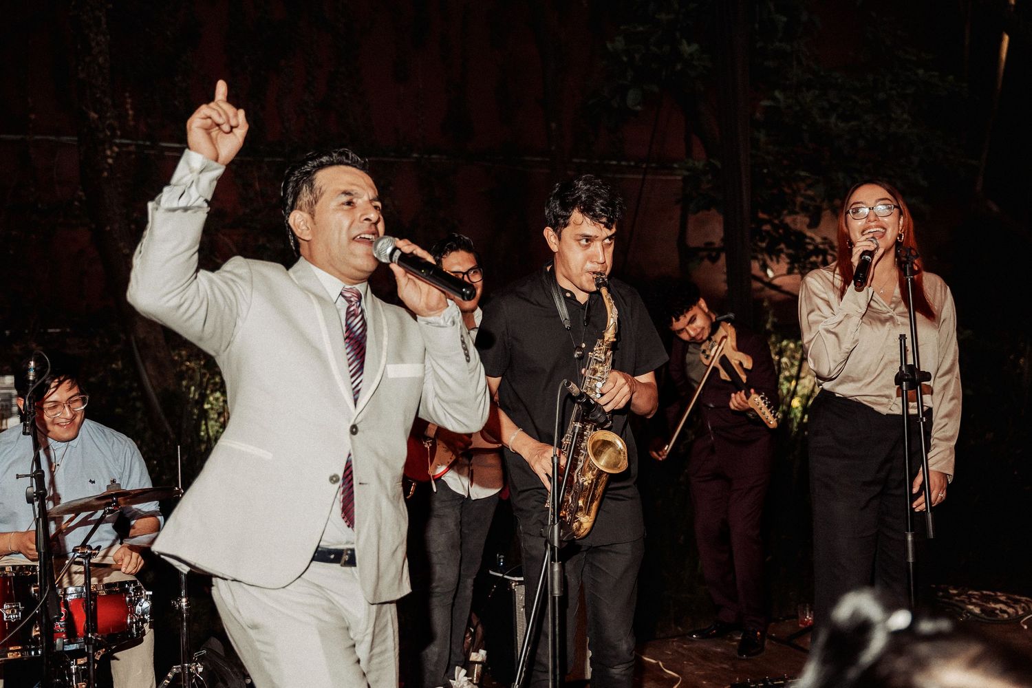 Live wedding band performs with saxophone and singer in white suit at an elegant evening reception.