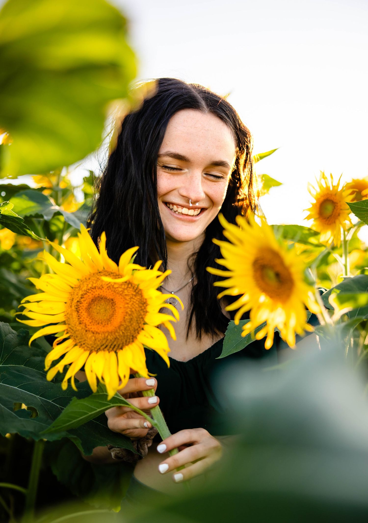 Natural light portrait among bright yellow sunflowers creating a cheerful garden scene.