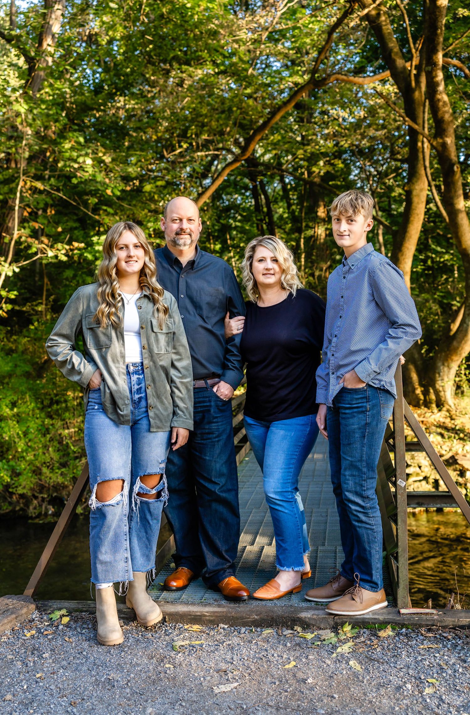 Casual group portrait on wooden bridge surrounded by lush green forest.