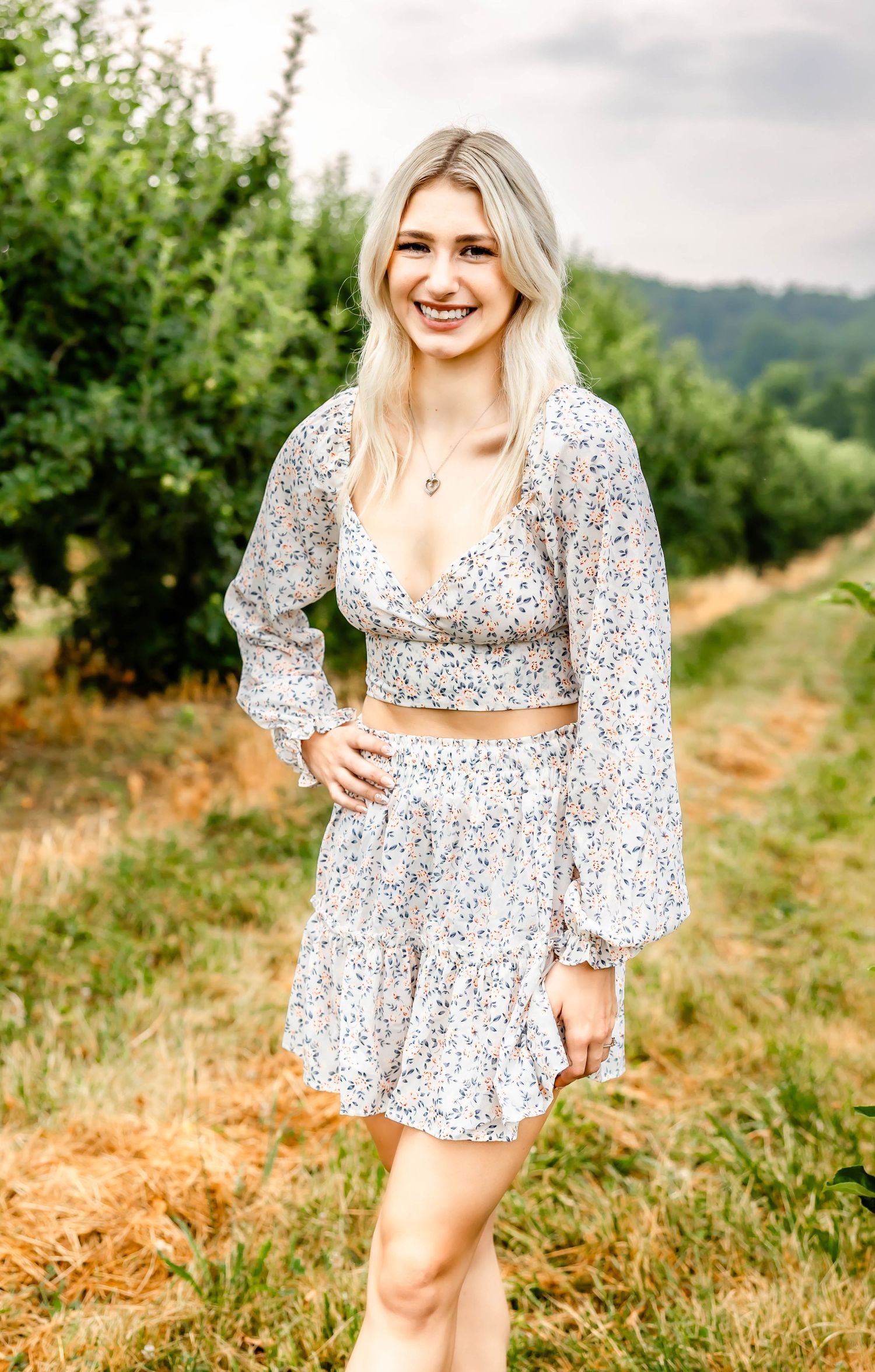 Summer fashion photoshoot featuring a white floral crop top and skirt set in a rural landscape.