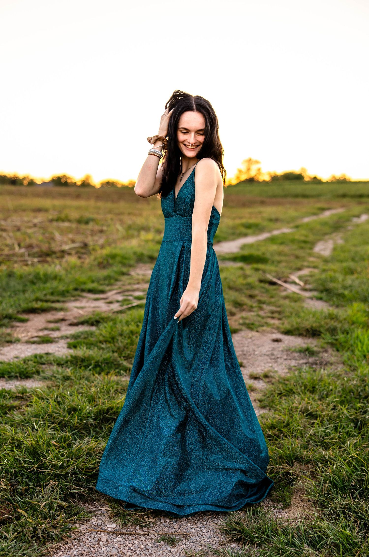 Joyful outdoor fashion portrait in flowing teal evening dress at golden hour.