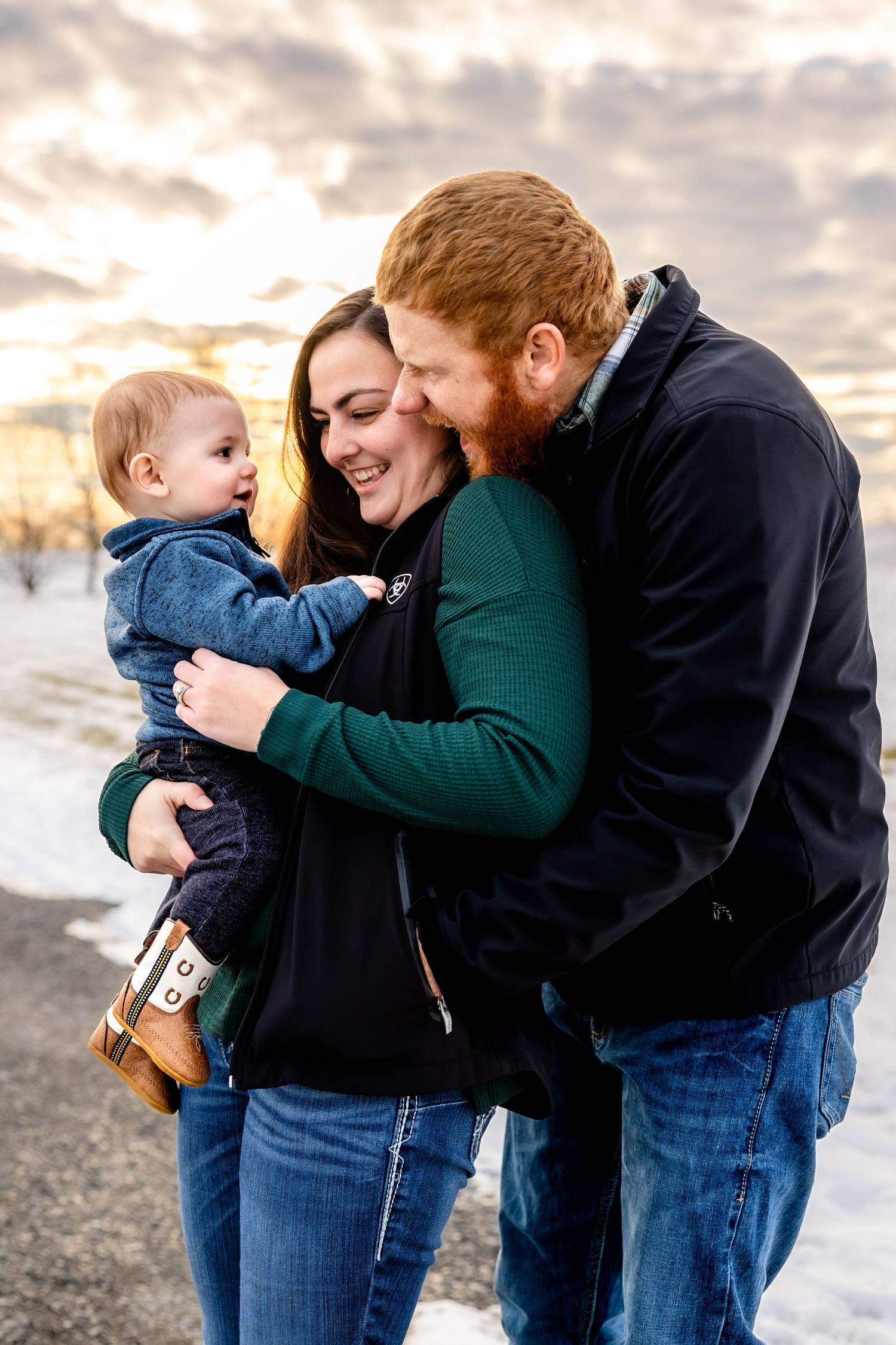 A tender family moment captured at sunset in a snowy winter landscape.