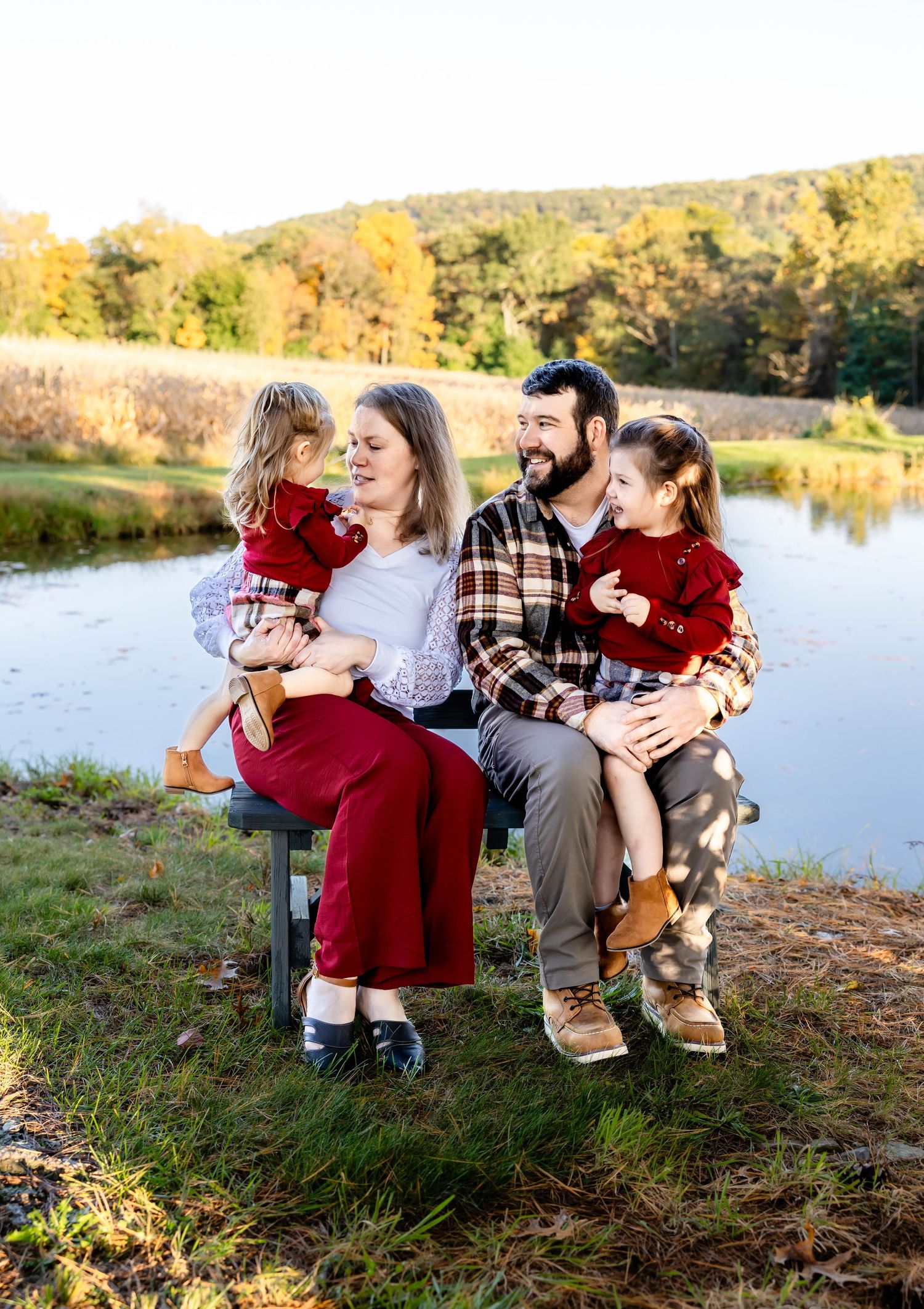 Family shares joyful moment together on bench by water during golden hour.