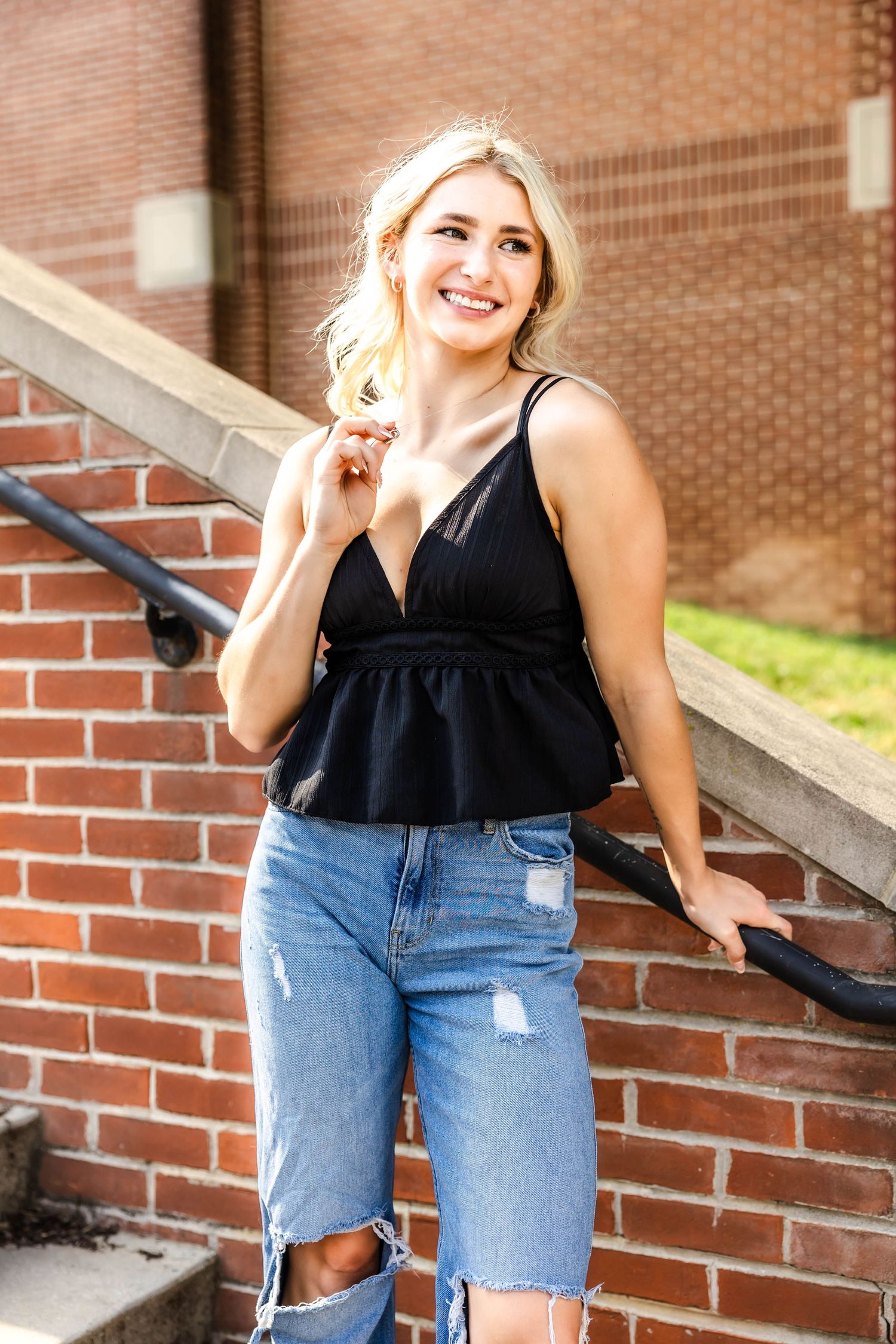 Summer fashion portrait on brick steps featuring black peplum tank and distressed denim.