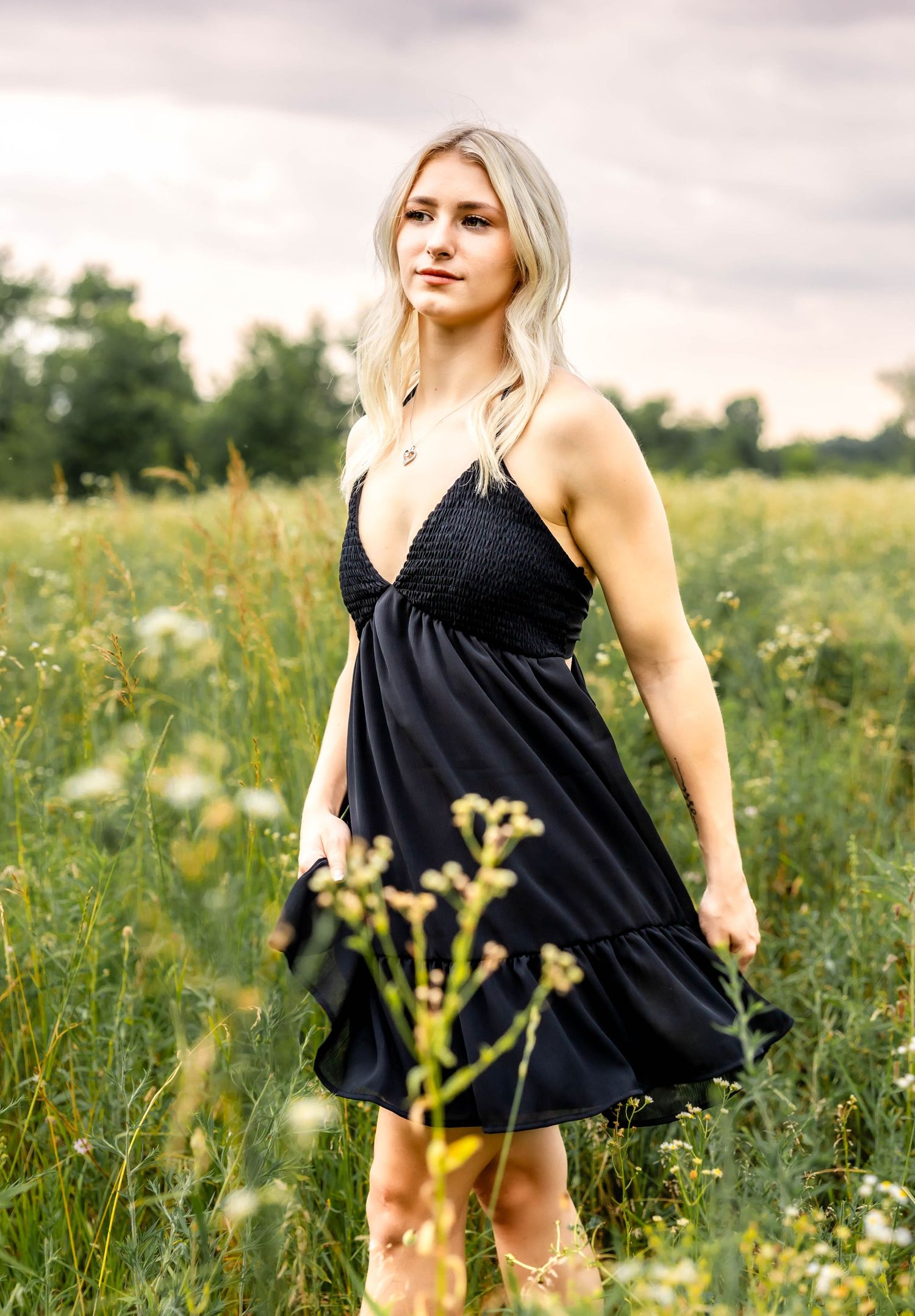 Black V-neck dress with sparkle detail photographed in a summer meadow setting.