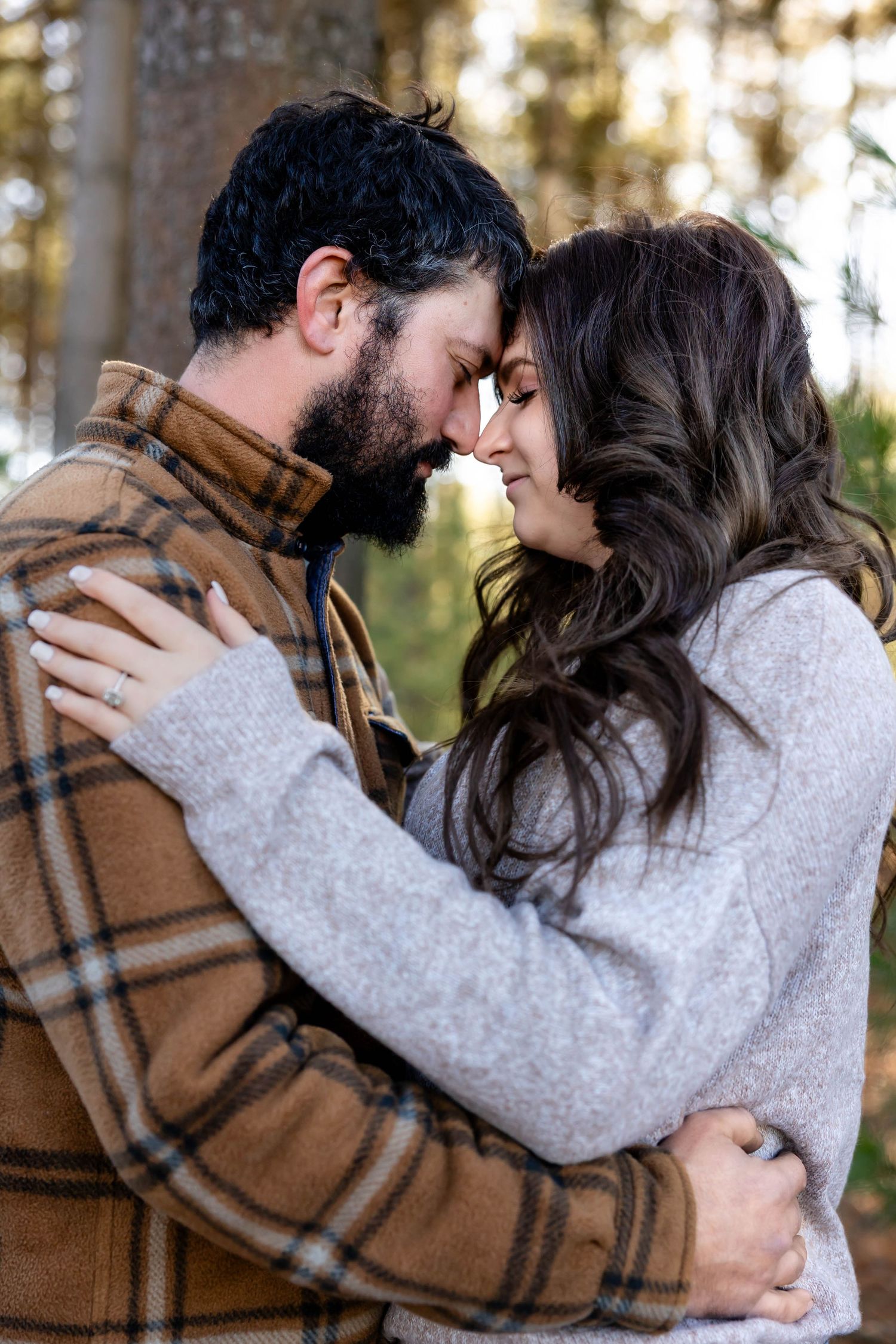 Intimate moment between couple in forest wearing cozy fall attire.