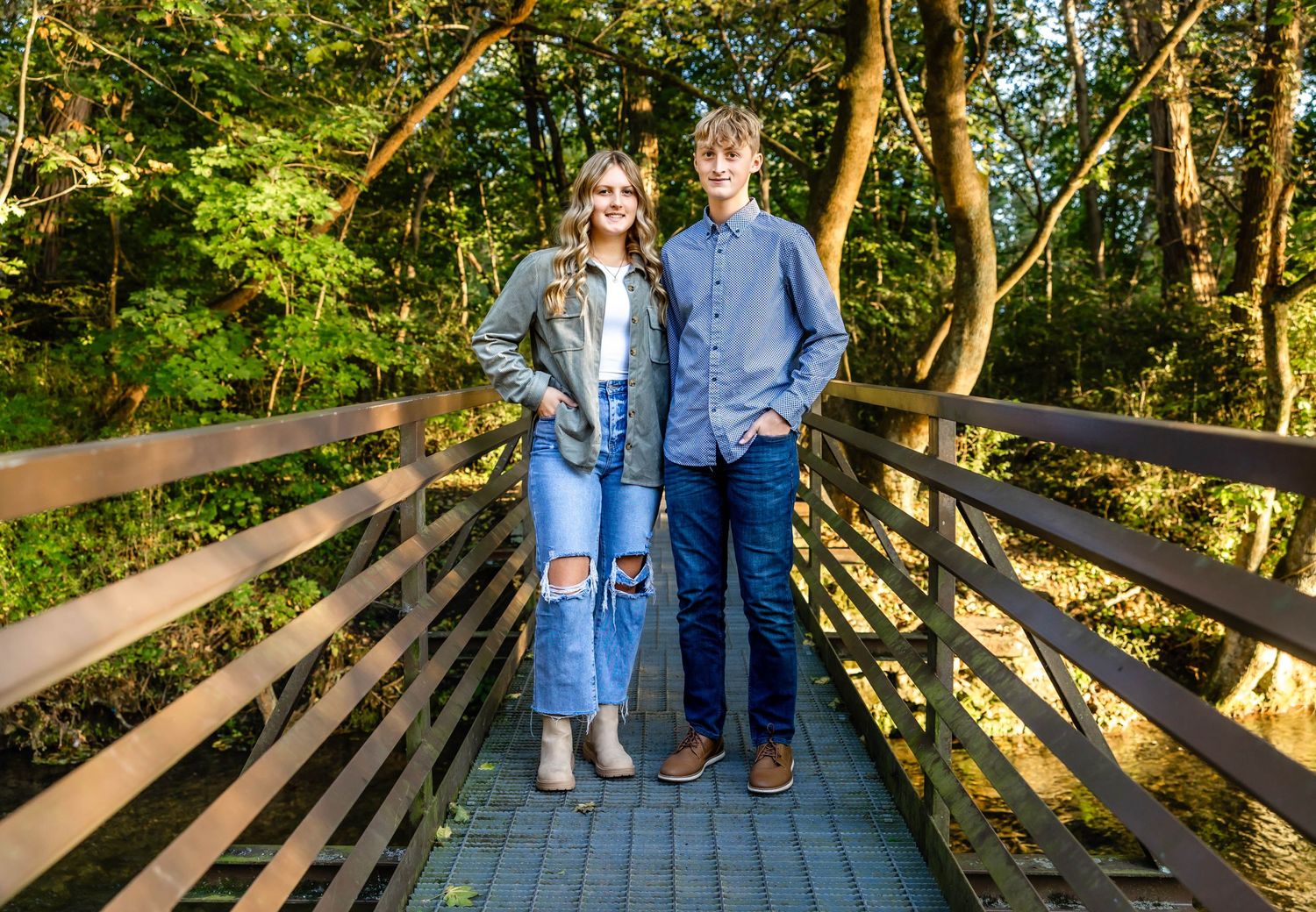 Two people standing on wooden walkway with forest scenery.