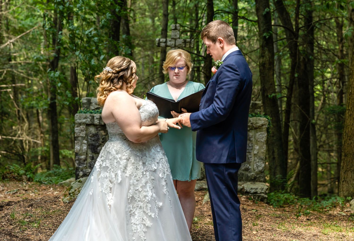 Intimate forest wedding ceremony with officiant and couple exchanging vows.