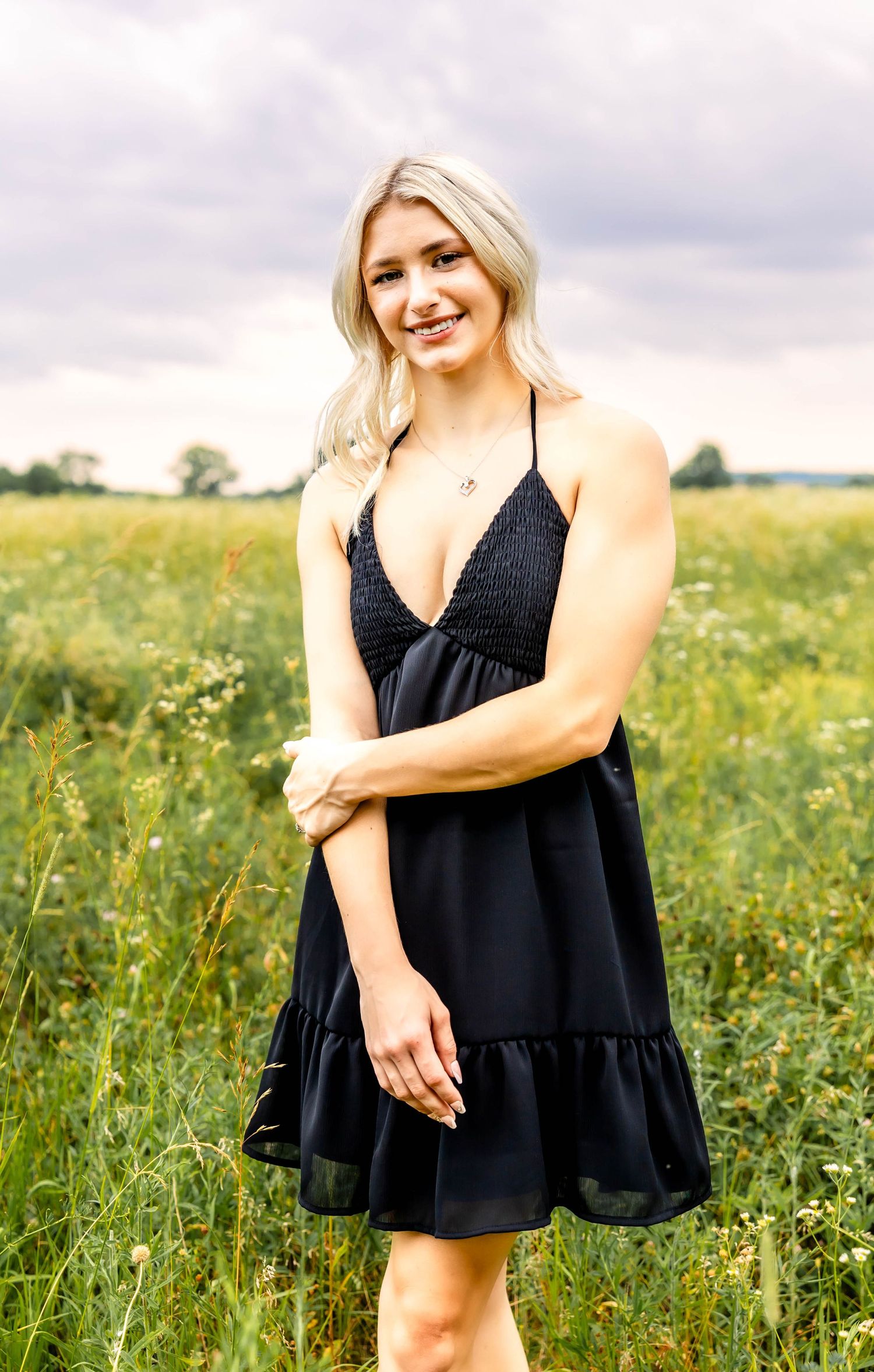 Black summer dress with ruffle hem shown in a blooming wildflower meadow.
