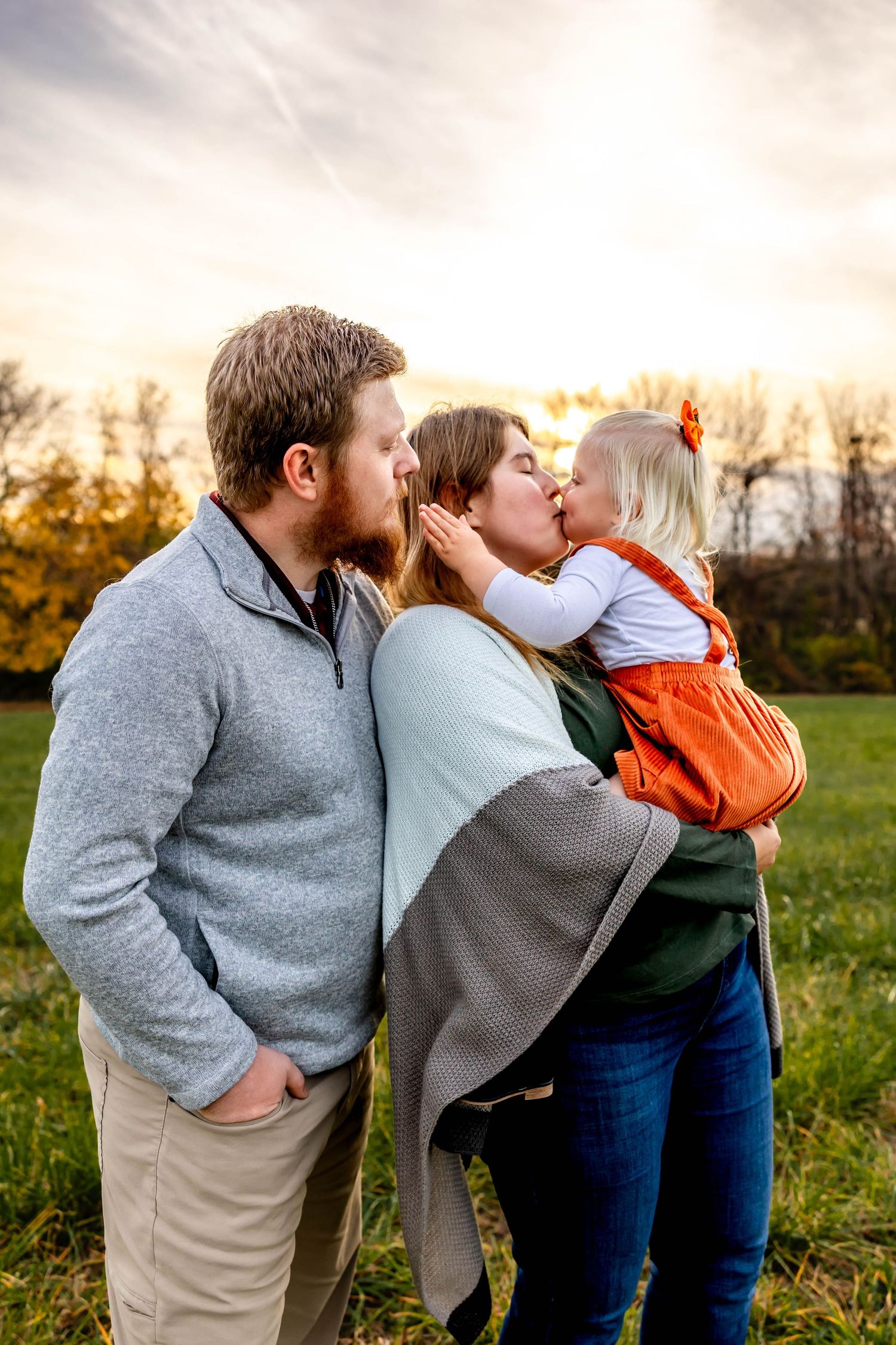 Family sharing affectionate moment in autumn field at sunset.