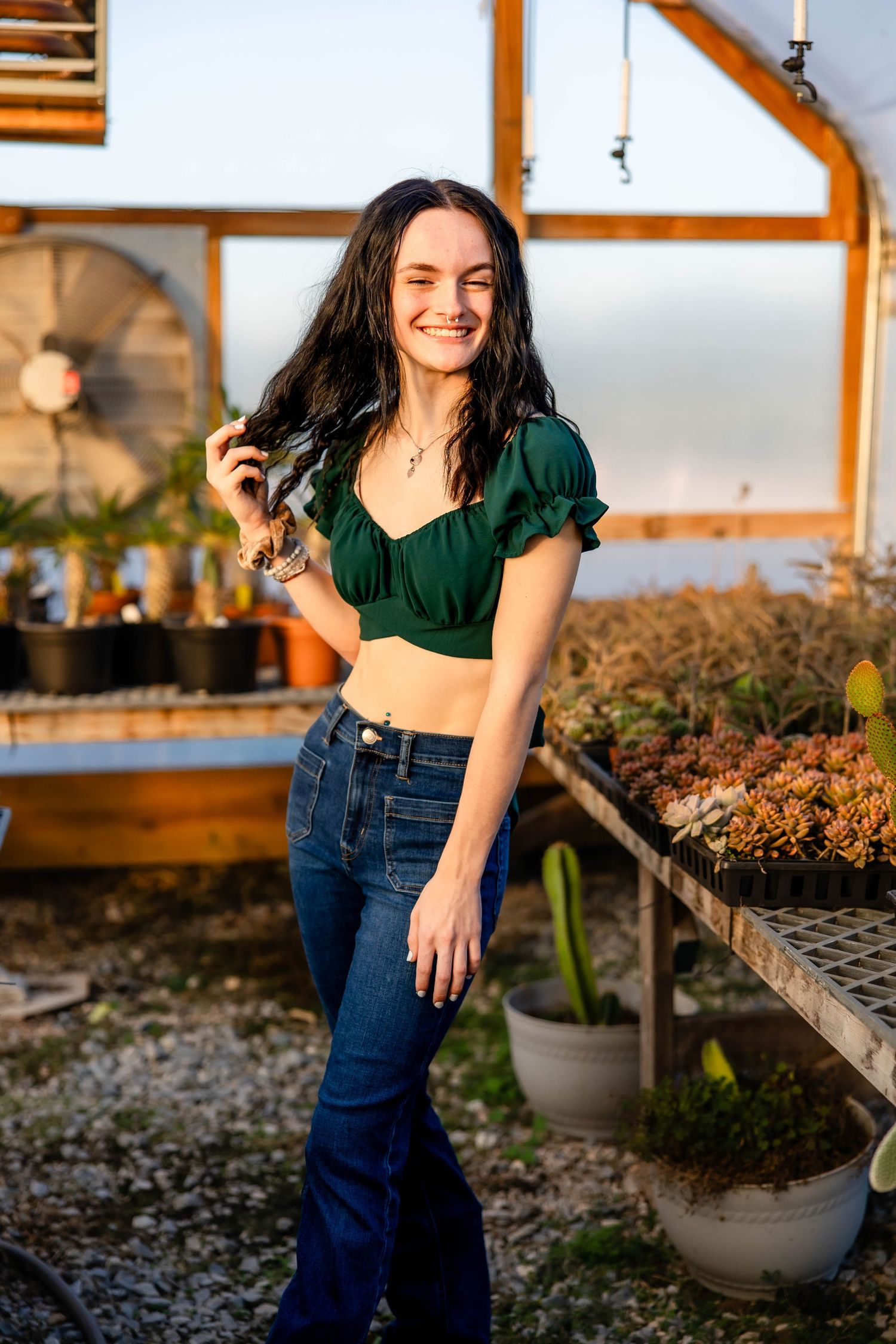 Candid greenhouse portrait with warm lighting and casual summer style.