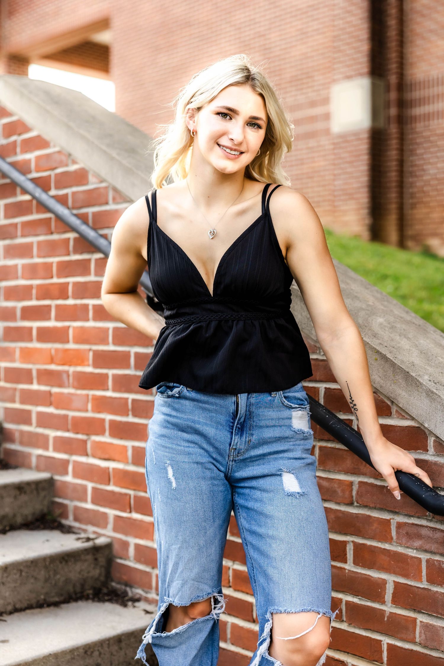 Stylish casual outfit with black peplum top and ripped jeans against brick wall background.