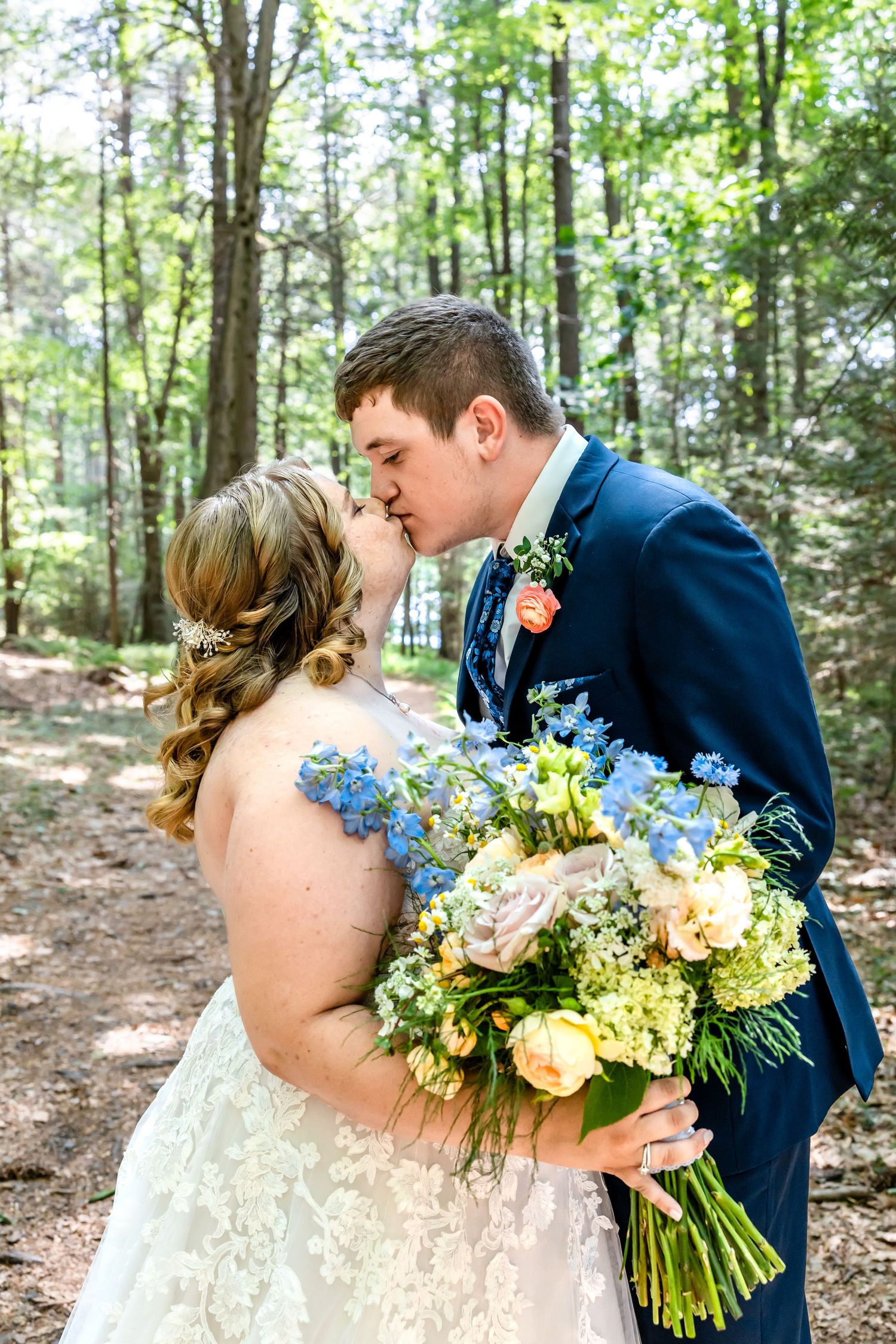 A romantic woodland wedding scene with a beautiful floral bouquet in blue and yellow.