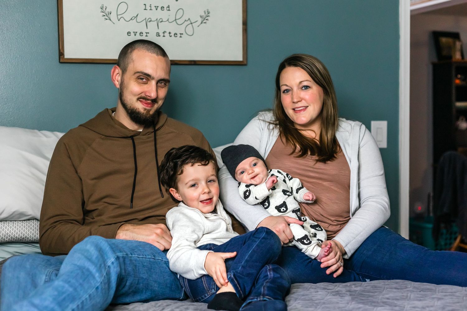 Family relaxing together on blue couch with toddler and infant wearing panda print outfit.